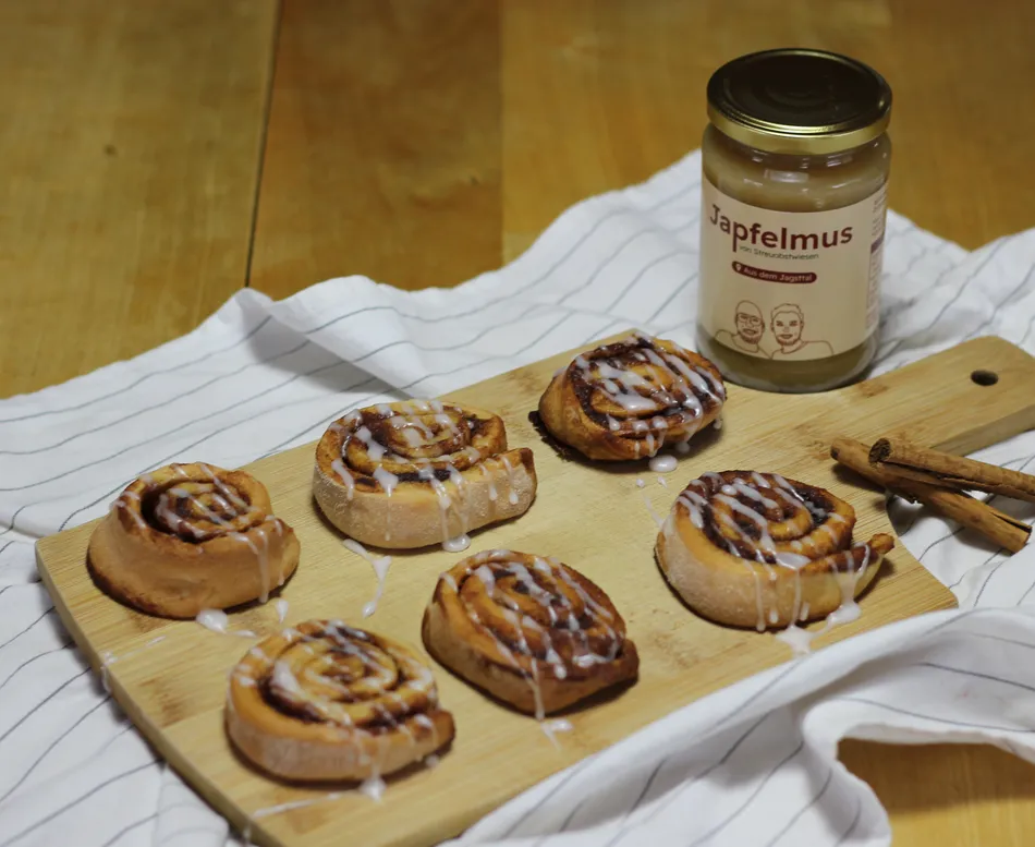 6 Zimtschnecken neben einem Japfelmus-Glas